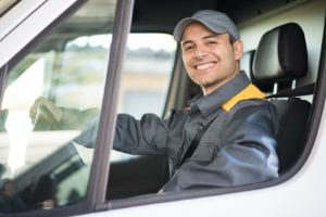 man sitting in drivers seat of work van and smiling